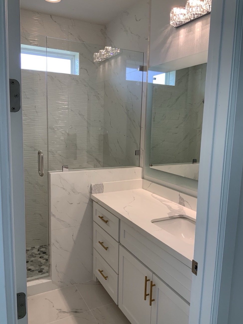 Marble bathroom with glass shower, custom vanity, and gold fixtures