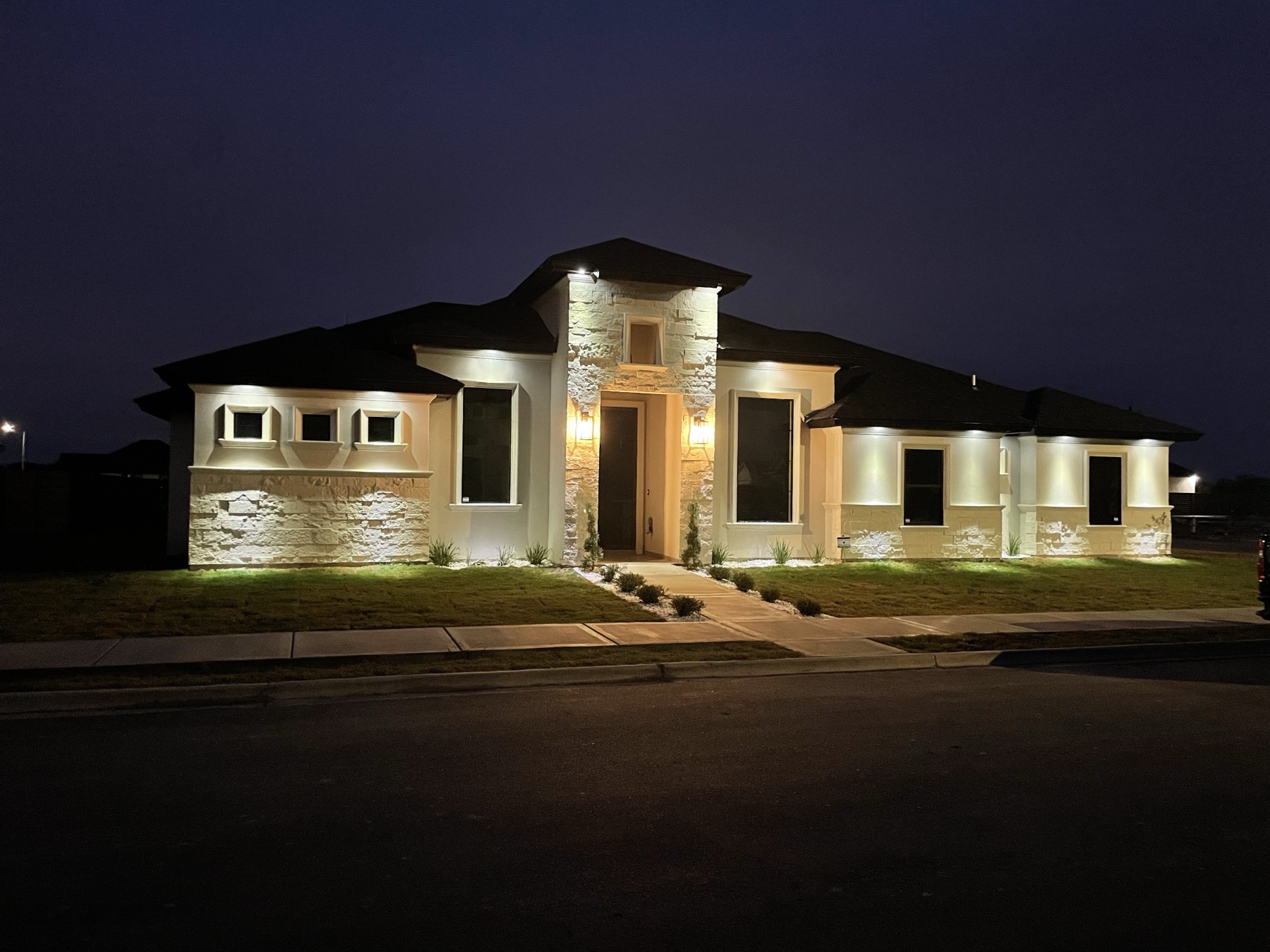 Stone and stucco custom home illuminated at dusk